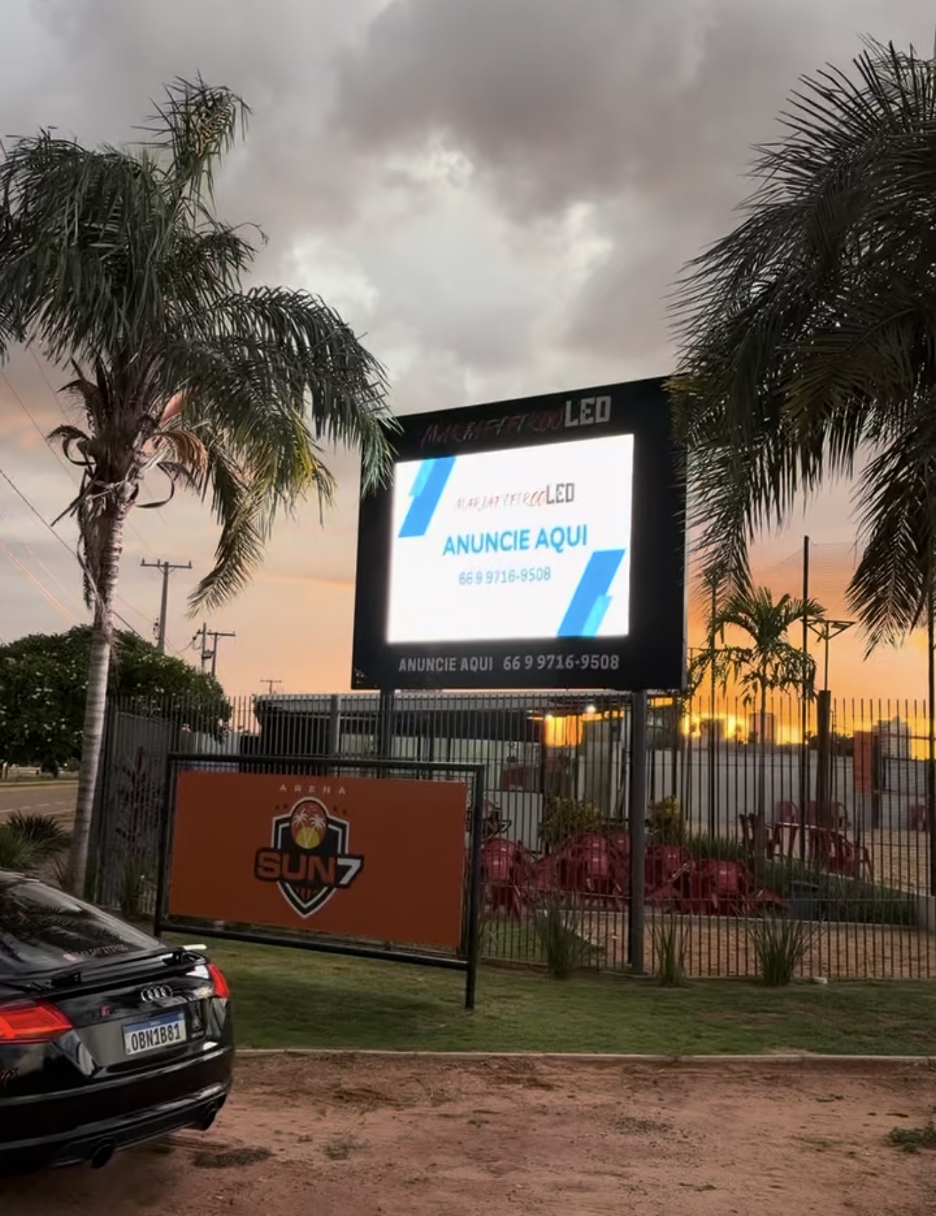 Painel de LED ao pôr do sol com anúncio Anuncie aqui e um carro em frente